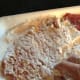 Using the flour that is around the cube steak, pick it up and put it on the top to coat it.