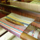 This loom with the spindle on top shows the work that goes into making patterned fabric.