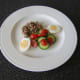 Salad and egg are plated with a thick slice of jellied ox tongue