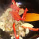 Peppers and onions added to wok with duck leg meat