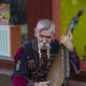 A Ukrainian wearing traditional garb, playing the bandura (a Ukrainian, plucked string, folk instrument)