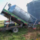A flatbed truck with a hoist is used to set the bin onto the barrels.
