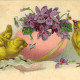 Two Easter chicks and a butterfly with pink Easter egg filled with violets