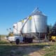 The skilled operator sets this 4,000 bushel bin slowly in place while a ground crew helps guide it with ropes.