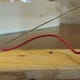 Attachment of the straightened paper clip to the board. The free end with the bent loop must be only a few millimetres above the nail head of the electromagnet.