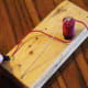 Use the alligator clip attached to the negative end of the battery to tap the thumb tack and listen to Morse code.