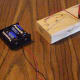 Attachment of the positive terminal of the battery to the bare wire of the other free end of the electromagnet.