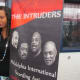A young lady poses with the banner for The Intruders singing group.