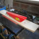 Using a bench saw to cut the wood to the desired width.