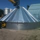 A finished roof and first ring await further developments. The bin is held down at the peak with the forks of a large forklift.