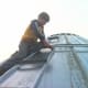 A person with a box-end wrench assists on the outside of the roof to hold the bolts still.