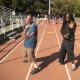 Jamie and Glenn step back into Neutral Bow stances. Note that their front toes are in line with their rear heels, as shown by the white lines on the track. Also note that their center-lines are covered by body angles and their hands.