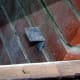 Four metal brackets, one in each corner, screwed in place to support the top glazed window frame to the cold frame.
