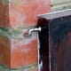 Illustration of the front of the cold frame firmly held in place to the front of the brick BBQ with a simple hook and eye near the top on either side of the front panel.