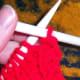 Pull the yarn between the needles to hang down the front of the project.