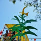 View of some band members and a metal tree with a yellow bird on top of it.