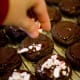 Sprinkle the candy cane pieces on top of the melted chocolate. When the chocolate hardens, it will keep the candy cane pieces attached.