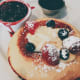 Restaurant pancakes served with fresh cream, blueberry compote, and maple syrup
