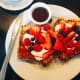 Restaurant French toast topped with fresh fruit and served with maple syrup