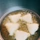 Fry the samosas in a pan.