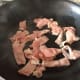 Frying sliced bacon.