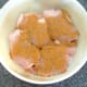 Curry powder and seasoning is scattered over chicken thighs