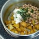 Combining potato and chickpea salad ingredients