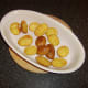 Mini potato wedges are added to a warm dish and a low oven
