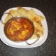 Naan bread slices are arranged around the cod fish curry