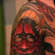 A red hannya tattoo with a snake between her teeth.