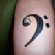 An F-clef tattoo with a yin yang inside it.
