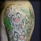 The faces in this colorful tattoo are very clown-inspired.