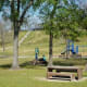 View of picnic tables, playground, and hill