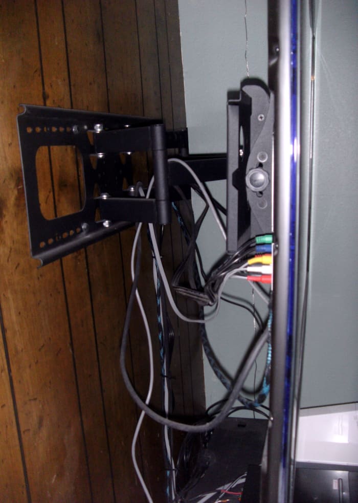 A cheetah bracket in use. This one is mounted in a corner of the room, and allows the TV to be rotated to face the center as well as tipped down slightly.