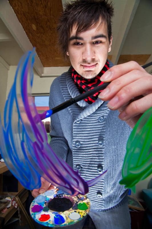 An artist paints on glass. Discover some ideas for selling your artwork, from drawing caricatures to designing t-shirts.