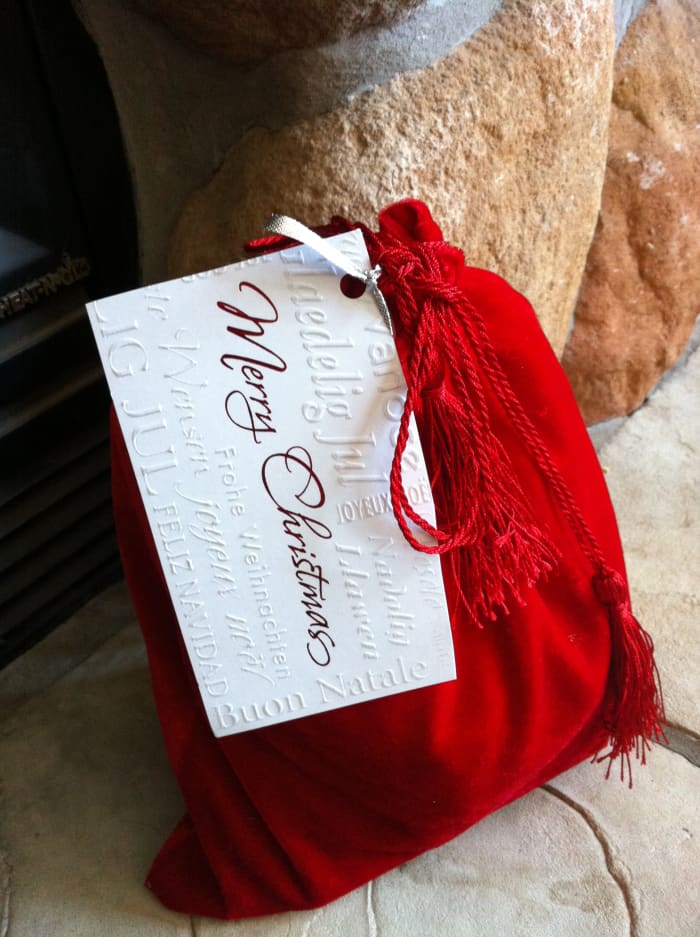 Christmas gift wrapped in a reusable velvet bag with gift tag made from a recycled Christmas card.