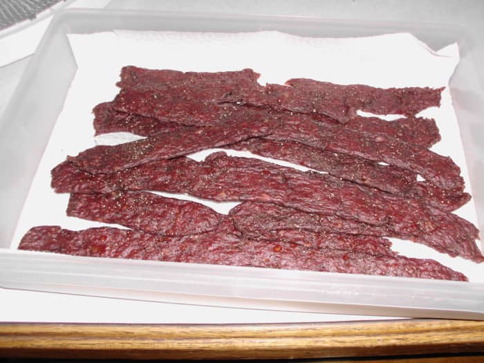 Deer jerky all done and cooling down on paper towels. You can dab the shinny grease spots off to help it dry and cool.