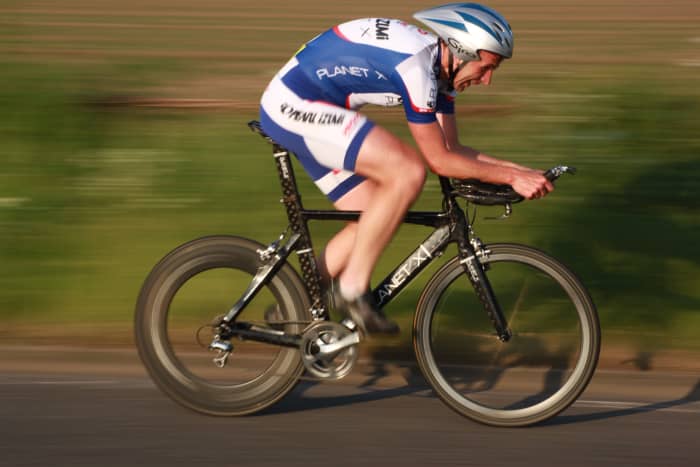 A cyclist competing in a Time Trial on a specific time trial bicycle- A Planet X Stealth with deep section Planet X carbon wheels.