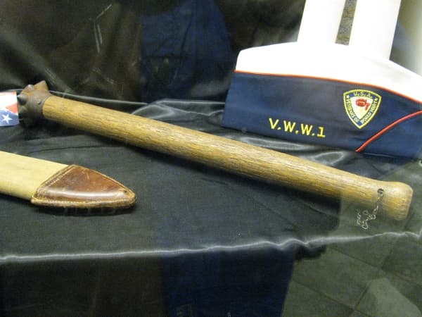 A trench raiding club with a spiked head in the centre of the photograph