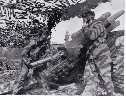 A 105mm howtizer crew preparing to fire (28th ID). The gunner corporal, who operates the quadrant (scope measuring deflection), stands to the left.