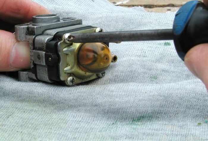4 screws hold the carburetor together. Remove the primer bulb retaining plate.