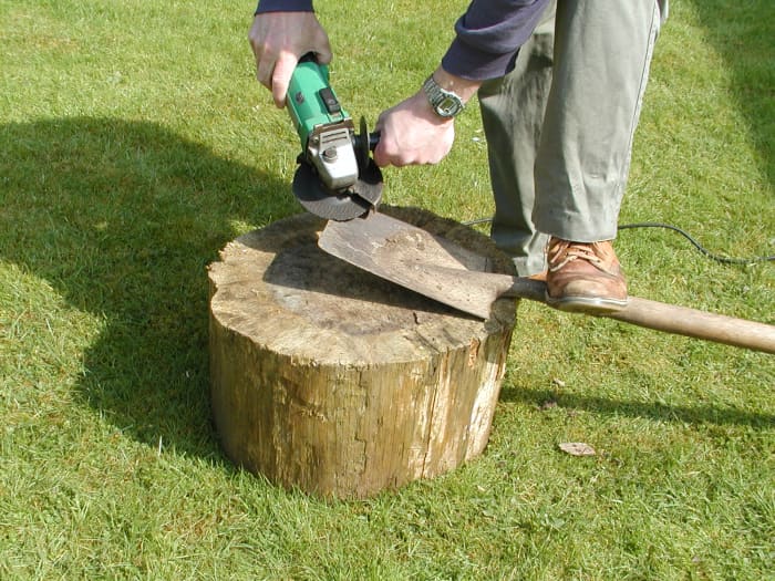 Place your foot on the spade to steady it. Angle the grinder at about 30 degrees to the plane of the blade
