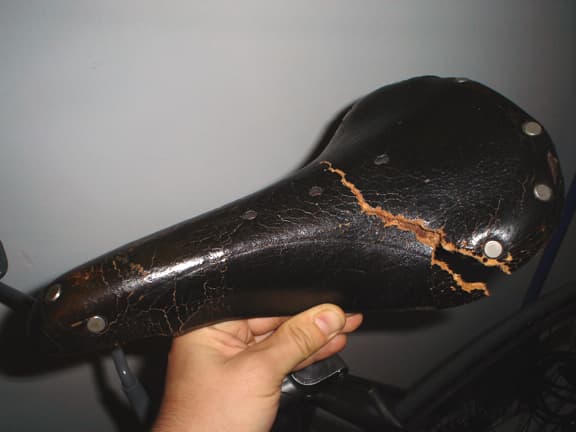 This dry rotten leather seat is falling apart, the leather is breaking apart because the fibers are so dry and crumbly.