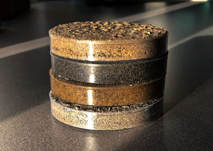 On the counter is a tier of samples of polymeric sand (for pavers) and polymeric stone dust (aggregated for natural stones) inside with details on the bottoms.