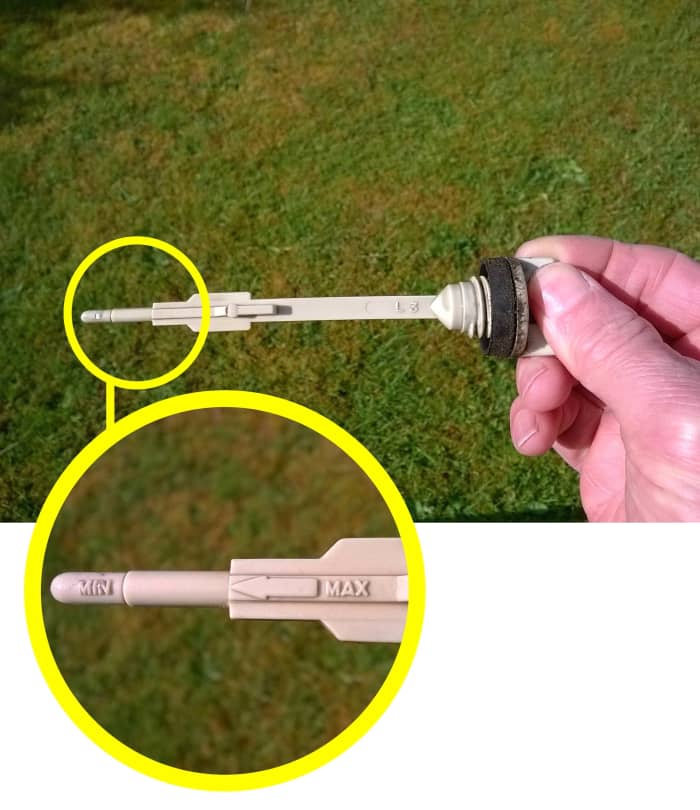 Checking the oil in a lawn mower. Oil level should be between the high and low marks on the dipstick