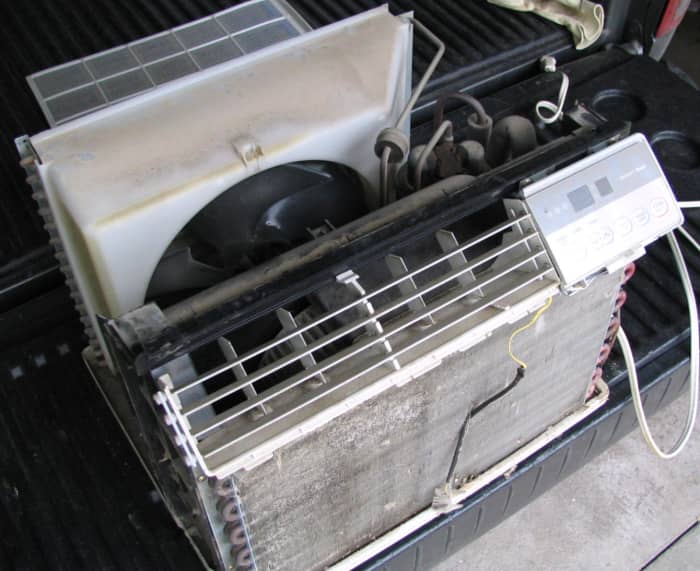 Removing the case exposes the coils, fan, and compressor. In a larger window unit, after the front plastic and a few screws are removed, the air conditioner will slide out of the case toward the inside of the room.