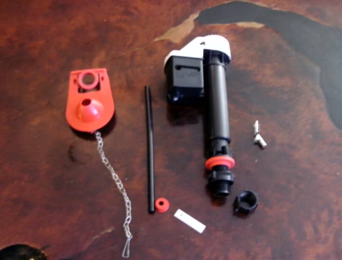 Parts from the new kit: flapper valve on the left and fill valve stem on the right. These don't match my old parts at all, and it doesn't have a float ball, but it will work fine.