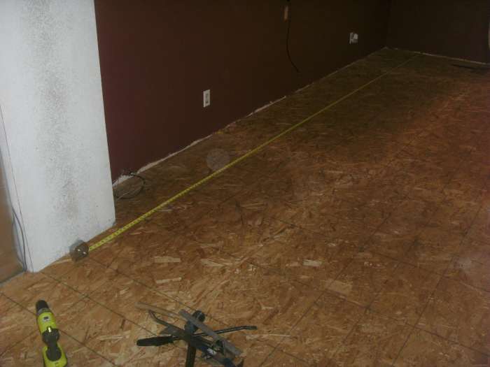 Checking the length of that first run of planks from the heating duct to the far wall. However long the first piece is it must not result in a final piece that is only a few inches long.