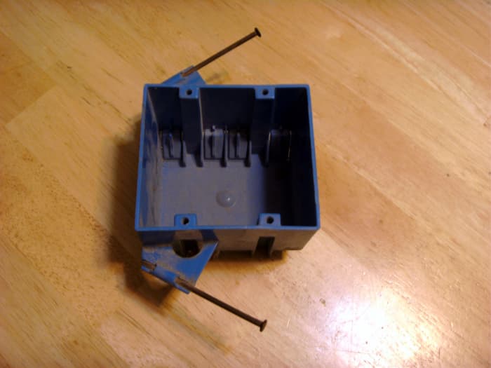 Although this is a 2 gang box rather than a single gang, the nails that will hold it to a stud are obvious. The stud will be on the left of the box and the nails driven in. It can only be used in new construction.