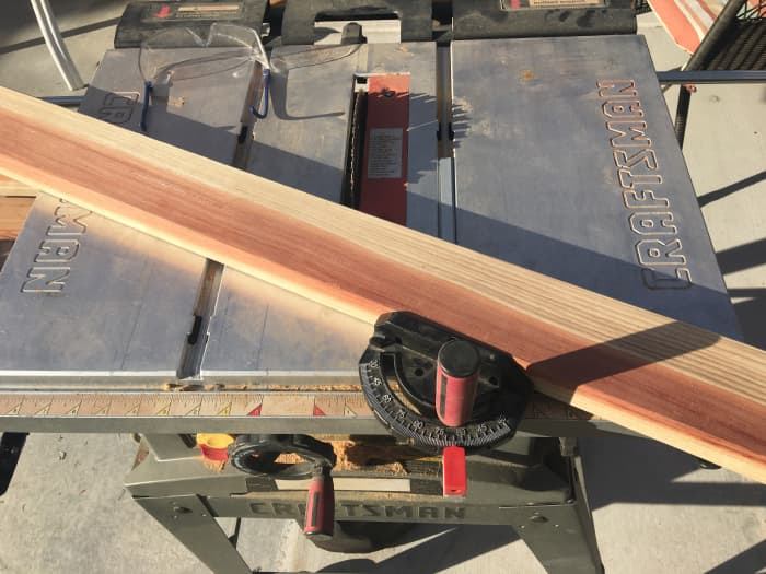 Using a table saw miter gauge to make an angle cut of 25 degrees by setting the indicator at 65 degrees. Line your pencil mark up with the blade to get the board length you measured.